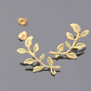 May include: A pair of gold leaf earrings. Each earring features a delicate branch with multiple leaves.