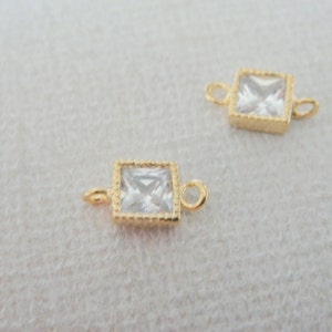 Peut inclure: Deux connecteurs carrés dorés avec des accents de cristal transparent. Chaque connecteur a deux boucles pour attacher des bijoux.