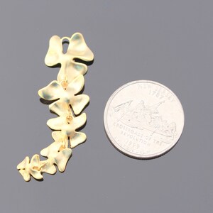 May include: A gold-colored metal chain of leaves, resembling a vine, with a total of 10 leaves. The chain is about the size of a US quarter.