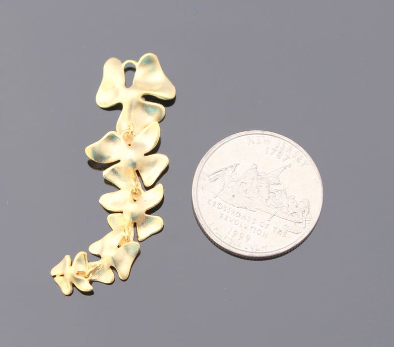 May include: A gold-colored metal chain of leaves, resembling a vine, with a total of 10 leaves. The chain is about the size of a US quarter.