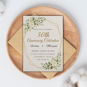 May include: An ivory-colored invitation for a 50th anniversary celebration, featuring floral accents and gold geometric lines. The text reads "50th Anniversary Celebration" with names and event details. The invitation is placed on a wooden plate with a matching envelope.