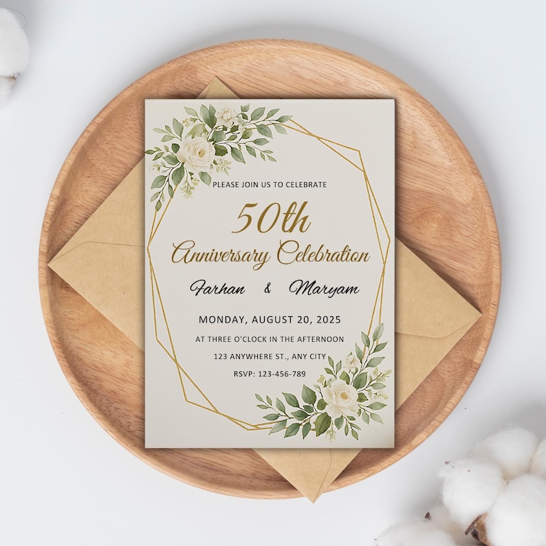May include: An ivory-colored invitation for a 50th anniversary celebration, featuring floral accents and gold geometric lines. The text reads "50th Anniversary Celebration" with names and event details. The invitation is placed on a wooden plate with a matching envelope.