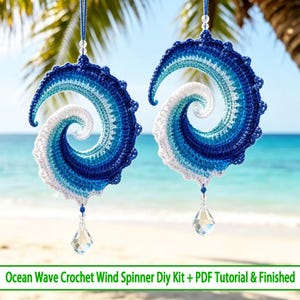 Könnte beinhalten: Zwei spiralförmige Häkel-Windspiele mit einem Meereswellen-Design in abgestuften Weiß-, Hellblau- und Dunkelblautönen. Jedes Stück hängt an einer blauen Schnur mit einer transparenten Perle und einem klaren Kristallanhänger an der Unterseite.