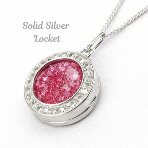 Op de afbeelding: Zilveren locket ketting met een ronde hanger. De hanger heeft een glinsterend roze midden, omringd door heldere kristallen. De tekst "Solid Silver Locket" staat boven de hanger. De ketting is van zilver.