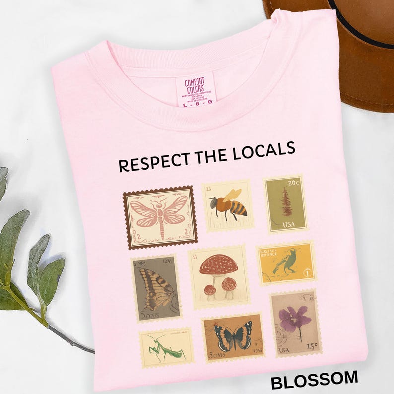 May include: A light pink t-shirt with the text "RESPECT THE LOCALS" and the word "BLOSSOM". The shirt features a collection of postage stamp designs with insects, mushrooms, and flowers.