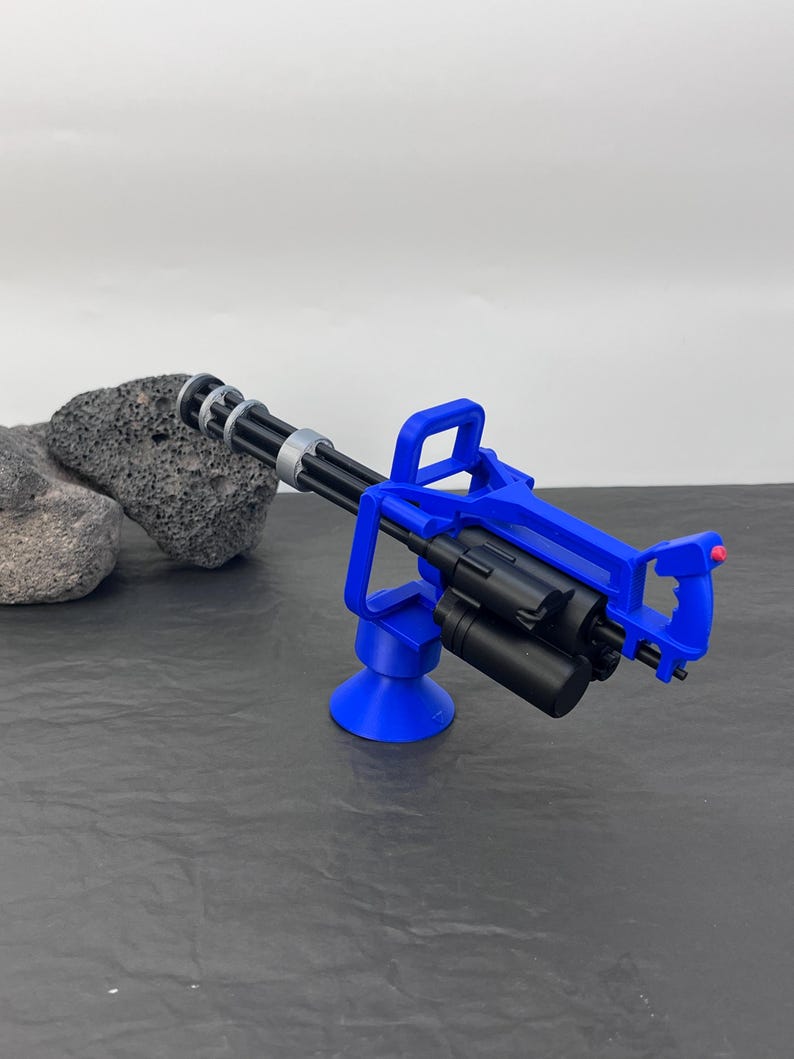 Pu&ograve; includere: Una minigun giocattolo blu e nera. La pistola presenta un design a canna rotante ed &egrave; montata su una base blu. L'impugnatura ha un pulsante rosso. Il giocattolo &egrave; realizzato in plastica ed &egrave; progettato per assomigliare a una vera minigun.