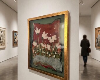 May include: A framed artwork featuring a textured, layered composition with white floral shapes against a deep red background, set above a mottled grey base. The piece is enclosed in a thick, metallic gold frame with a weathered, rustic finish.