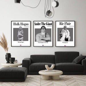 May include: Three framed black and white posters featuring professional wrestlers Hulk Hogan, Andre the Giant, and Ric Flair. Each poster includes the wrestler's name, a photo, and a quote. The posters are displayed above a dark gray sofa.