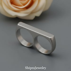 Minimalistisk tysk silverring med två fingrar för stöd vid artrit.
