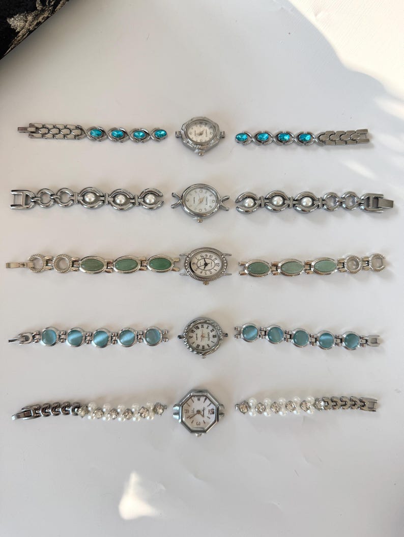 May include: Five vintage women's watches with silver-toned metal straps. Each watch has a unique design, with turquoise, pearl, and jade-coloured embellishments. The watch faces display Roman numerals and decorative elements.