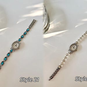 May include: Two elegant women's watches. Style 21 features a silver band with oval turquoise stones. Style 22 has a silver band with white pearls. Both watches have a round, silver watch face with a white background and black hands.
