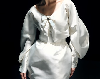 Vestido de novia corto de satén color marfil con mangas largas y corsé. NELLI