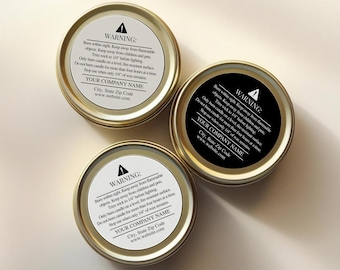 May include: Three round gold metal candle tins viewed from above. Two tins feature white circular labels with black text, while one tin has a black circular label with white text. Each label displays a warning symbol and safety instructions.