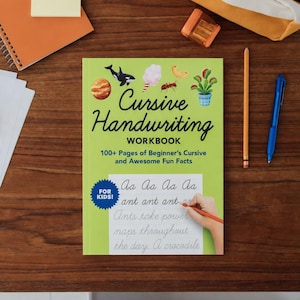 May include: A green "Cursive Handwriting Workbook" for kids, with colorful illustrations, a pencil, and a blue pen on a wooden surface. The workbook includes 100+ pages of beginner's cursive and fun facts.