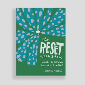 May include: A green workbook titled "The Reset Workbook" with a large teal and gray floral design. The book's subtitle reads "A Guide to Finding Your Inner Magic" by Justin Shiels.