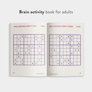 May include: An open brain activity book for adults, featuring two Sudoku puzzles. The left page has the text "ONE HUNDRED NINETY-TWO HARD" and the right page has "ONE HUNDRED NINETY-THREE HARD". The book is open to pages 196 and 197.