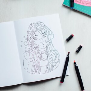 inside view of The Modern Manga Coloring Book sitting on a cream colored tabled surrounded by alcohol markers.