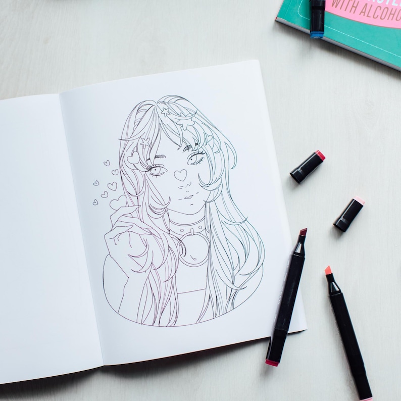 inside view of The Modern Manga Coloring Book sitting on a cream colored tabled surrounded by alcohol markers.