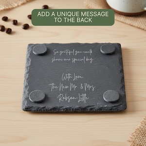 May include: A dark gray slate coaster with rounded corners and four gray pads on the bottom. The coaster has white script that reads, "So grateful you could share our special day. With Love. The New Mr. & Mrs Robson-Little."