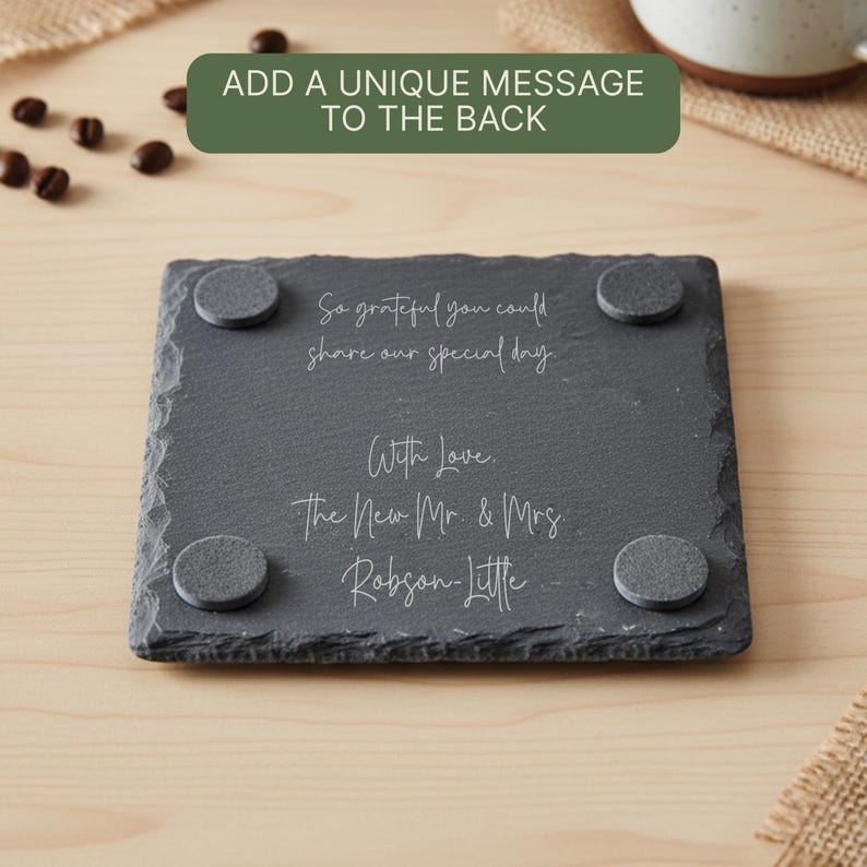 May include: A dark gray slate coaster with rounded corners and four gray pads on the bottom. The coaster has white script that reads, "So grateful you could share our special day. With Love. The New Mr. & Mrs Robson-Little."