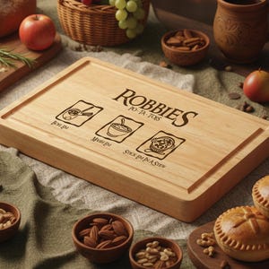 May include: A rectangular wooden cutting board with a carved groove around the edge. The board has the text "ROBBIES PO-TA-TOES" and three illustrated cooking instructions. Apples, nuts, and pies are arranged around the board.