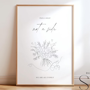 May include: A framed print with a minimalist floral line drawing. The artwork features the text "Pick a seat, not a side, we are all family." The design is in black on a white background, with a wooden frame. The artwork is a digital template.