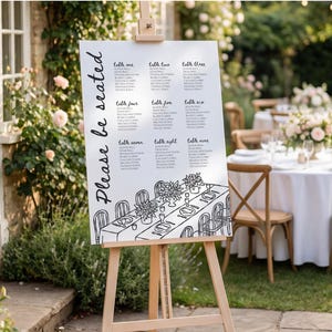 May include: A white rectangular wedding seating chart sign on a wooden easel. The sign features the black text Please be seated, a list of nine tables with guest names, and a black line drawing of a long dining table with floral centrepieces.