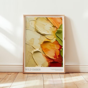 Puede incluir: Una impresión artística enmarcada con un diseño abstracto de gruesas pinceladas en crema, naranja, rojo y verde. La obra de arte se titula "WILD EMBER" en texto blanco. La impresión se exhibe sobre un suelo de madera.