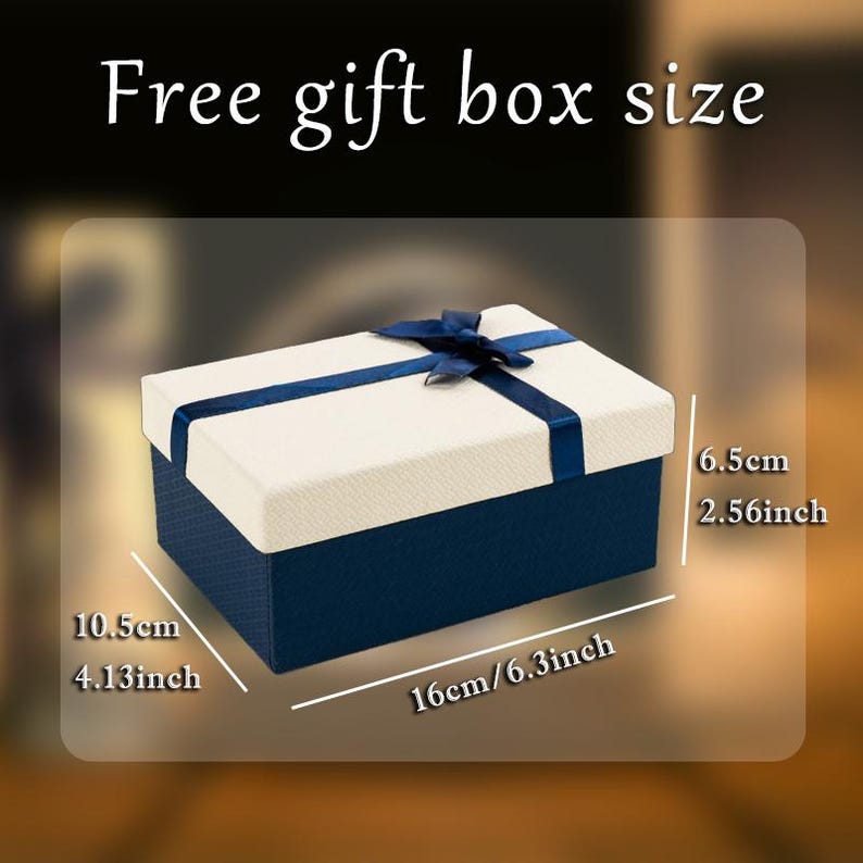 May include: A rectangular gift box with a navy blue base and a cream-colored lid. A navy blue ribbon and bow adorn the top. The box measures 6.3 inches long, 4.13 inches wide, and 2.56 inches high. Text on the image reads "Free gift box size."