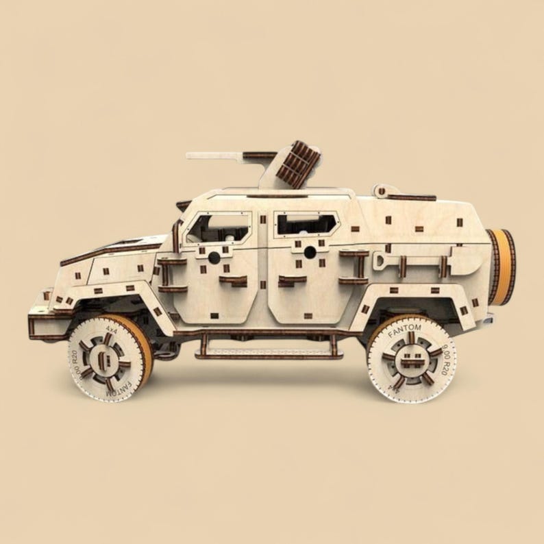 May include: A wooden model of a military vehicle with a light tan finish and brown accents. The model features detailed wheels, a turret, and a spare tire. The wheels have the text "FANTOM" and "R20" printed on them.