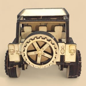 May include: A wooden model of a jeep, featuring a spare tire on the back. The vehicle has a light-colored body with dark brown accents, including the wheels and frame. The model has detailed cutouts and a roof.