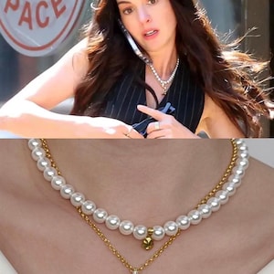 May include: A two-strand necklace featuring faux pearls and a gold-toned chain with a toggle clasp. The top strand is a classic pearl necklace, while the lower strand has a delicate gold chain with a small pendant.
