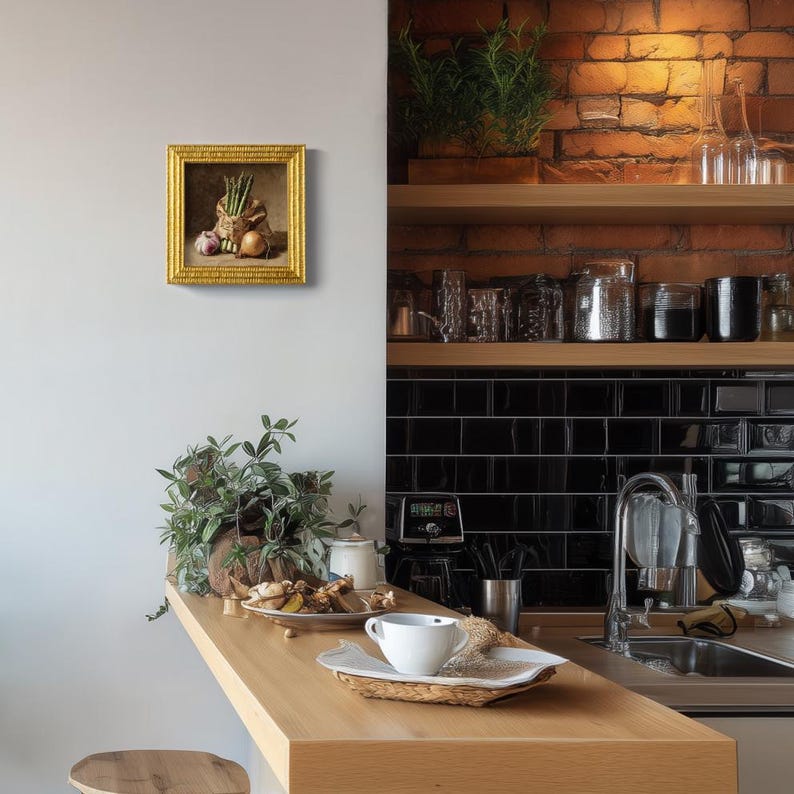 May include: A framed still life painting featuring a burlap sack filled with asparagus, garlic, and an onion. The painting has a gold frame and is mounted on a white wall. The kitchen has a wooden countertop and brick wall.
