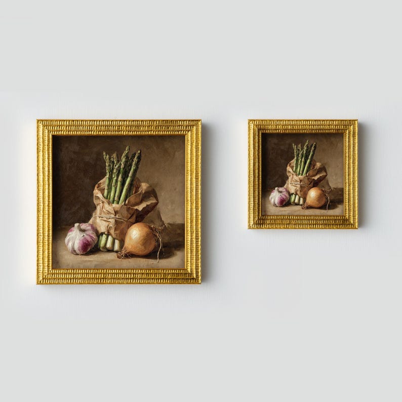 May include: Two framed paintings with gold frames. Each painting depicts a still life of vegetables: asparagus in a paper bag, a red onion, and a yellow onion. The background is a neutral brown.