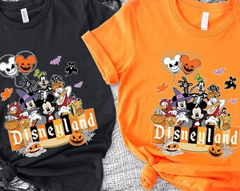 May include: A black t-shirt and an orange t-shirt, each featuring a graphic print of Disney characters in Halloween costumes, including Mickey Mouse, Minnie Mouse, and Goofy, with the text Disneyland and various pumpkin and ghost icons.