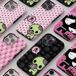 May include: A collection of phone cases with various designs. Some cases are pink with black polka dots or a pattern of skulls and hearts. Other cases are black with a skull pattern. Each case features a cartoon zombie character or a couple.