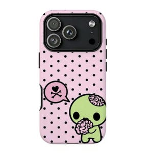 May include: A pink phone case with black polka dots and a cartoon zombie design. The zombie is green with a visible brain and is holding a brain. A speech bubble with a heart and crossbones is also featured.