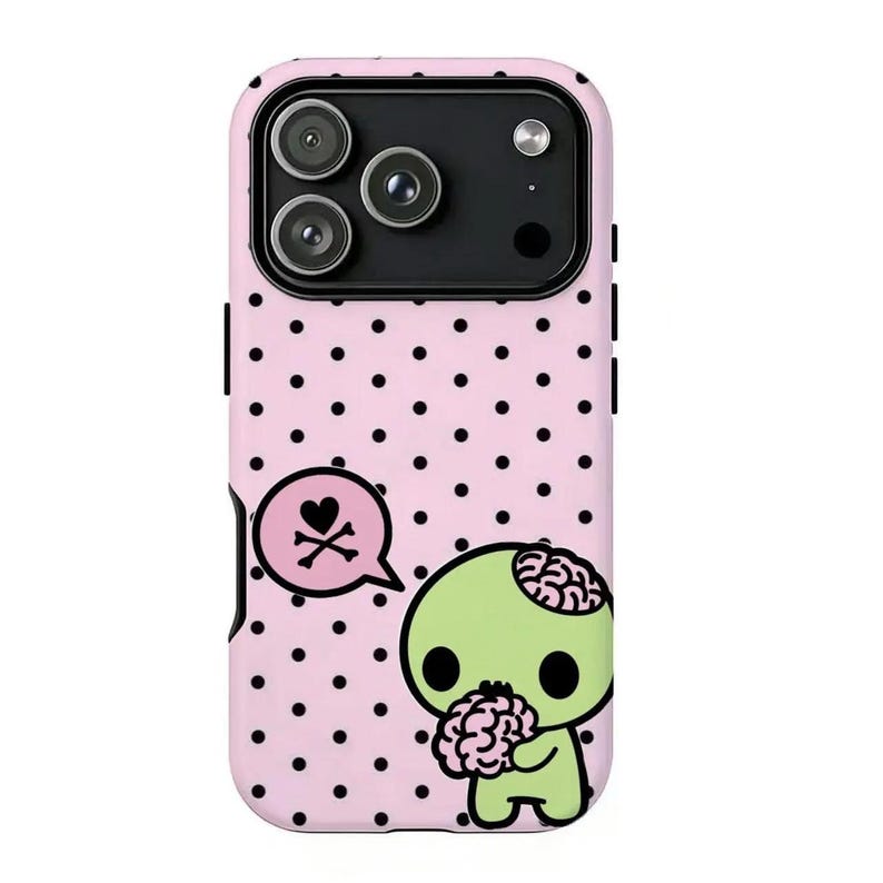 May include: A pink phone case with black polka dots and a cartoon zombie design. The zombie is green with a visible brain and is holding a brain. A speech bubble with a heart and crossbones is also featured.