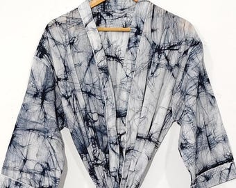 May include: A white and navy blue patterned robe hangs on a wooden hanger. The robe is tied at the waist with a matching belt. The pattern has a tie-dye effect. The robe is displayed against a white background.