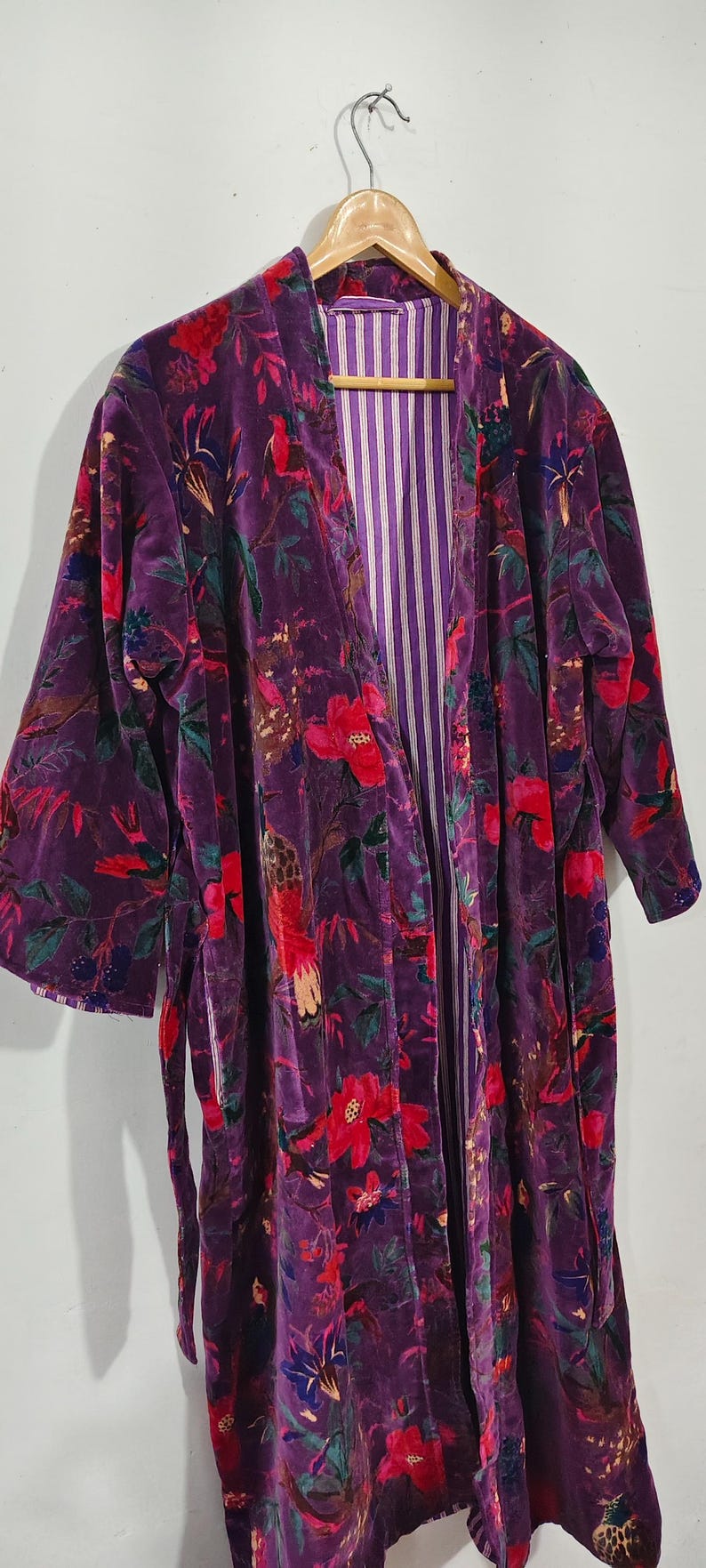 Puede incluir: Bata larga con frente abierto en un tono p&uacute;rpura intenso, adornada con un vibrante estampado floral en rojo, verde y azul. El interior de la bata presenta un forro a rayas. La bata est&aacute; hecha de un material suave y aterciopelado.