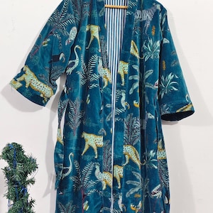 Puede incluir: Bata de color turquesa con estampado de animales de la jungla, incluyendo leopardos, cebras y p&aacute;jaros. La bata tiene un forro a rayas y est&aacute; colgada de una percha de madera. La bata est&aacute; hecha de un material suave y aterciopelado.