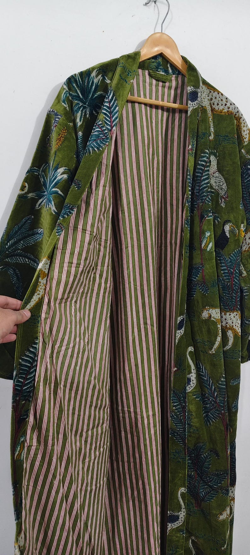 May include: Green velvet robe with a tropical print featuring toucans, leopards, and palm trees. The robe's interior has a striped pattern in shades of green and red. A stylish, long-sleeved garment.