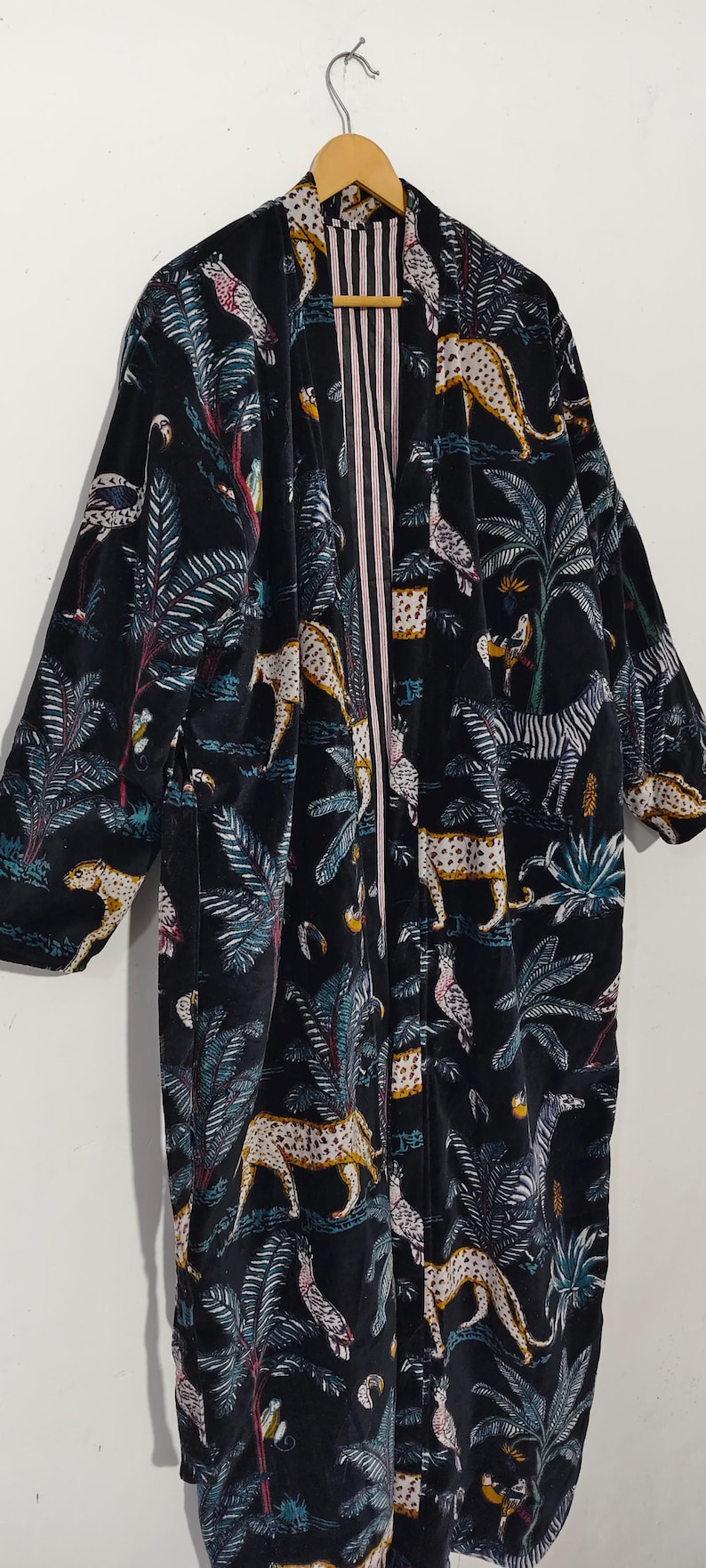 Puede incluir: Bata tipo kimono de terciopelo negro con un estampado de jungla vibrante con leopardos, cebras, p&aacute;jaros y palmeras. La bata tiene un forro interior a rayas.