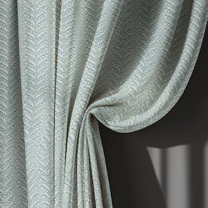 May include: Close-up of a light green curtain with a repeating leaf pattern. The fabric is textured and drapes in soft folds. The curtain is partially drawn, revealing a dark gray wall and shadows.