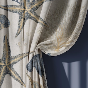 May include: Beige curtain fabric with a repeating pattern of starfish, seashells, and coral in shades of blue and gold. The fabric is draped, revealing the texture and design. The curtain is against a dark blue wall.