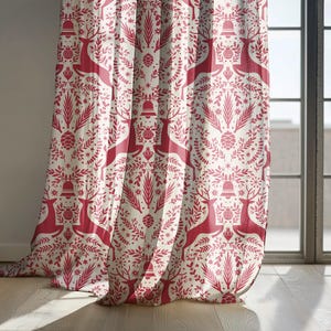 May include: Cream-colored curtain with a repeating pattern of red reindeer, bells, and botanical elements. The design includes pinecones, stars, and stylized foliage, creating a festive, holiday-themed aesthetic. The curtain is hanging near a window.