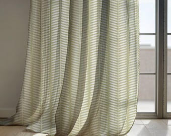 May include: Light green and white patterned curtains hanging in front of a window. The curtains have a repeating chevron design. The curtains are made of a lightweight fabric and are partially see-through, allowing light to filter through.