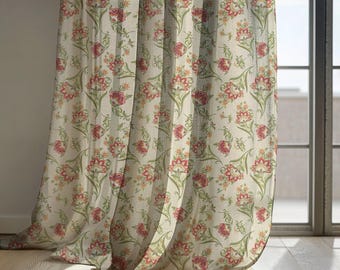 May include: Cream-colored floral curtains with a repeating pattern of red and green flowers and leaves. The curtains are hanging in front of a window, with sunlight streaming through. The curtains are made of a lightweight fabric.