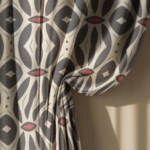 May include: Curtain fabric with a repeating geometric pattern. The design features gray oval shapes with diamond and leaf-like details, accented with small red ovals. The fabric is draped, revealing the pattern's texture and color variations.