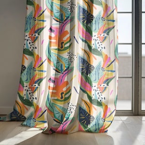 May include: Sheer curtain panel with a vibrant tropical leaf pattern. The design features large leaves in shades of orange, pink, blue, and green, accented with black polka dots, against a cream background. The curtain hangs near a window with natural light.